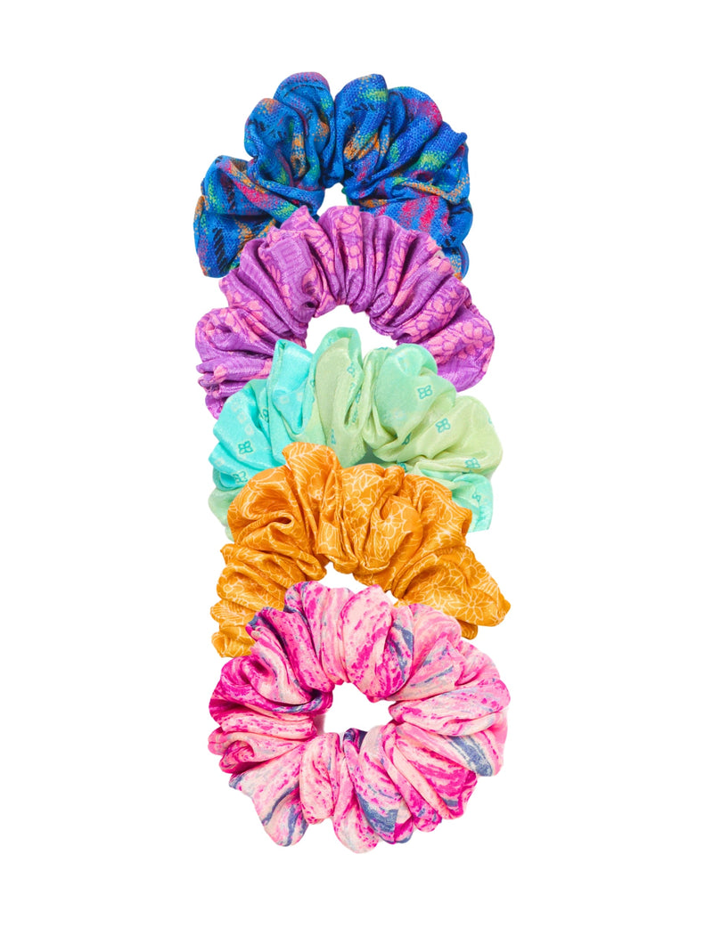 Set of five colorful fabric scrunchies in blue, purple, mint green, orange, and pink with various patterns, flat lay