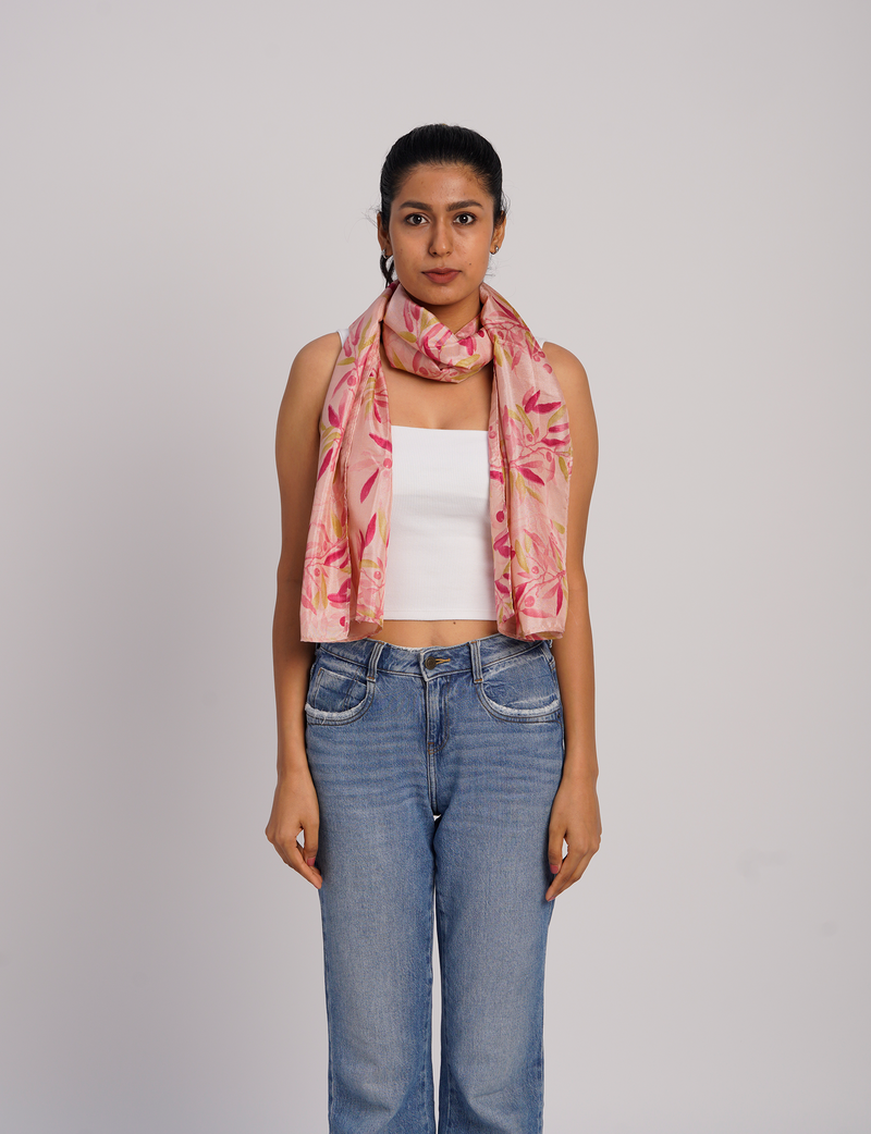 Woman wearing a pink stole with red and yellow floral print, paired with white sleeveless top and blue jeans, front view