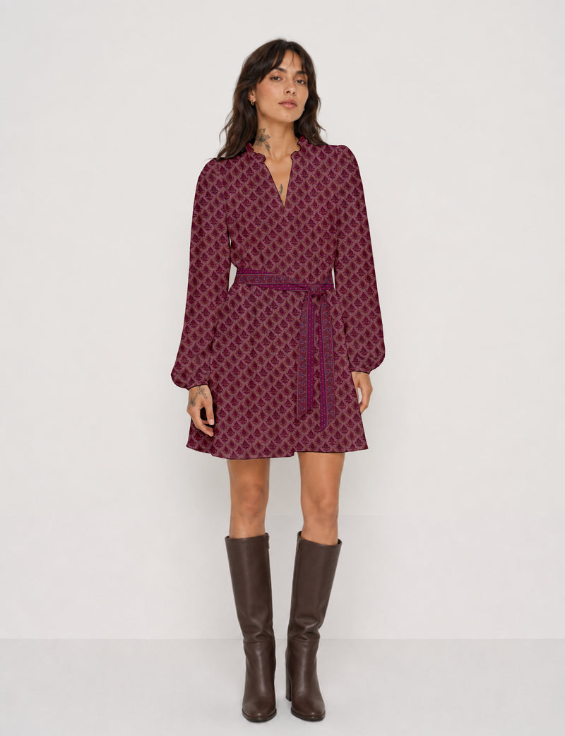 Woman wearing a long-sleeve pink leaf patterned swing dress with a matching belt and brown knee-high boots, front view