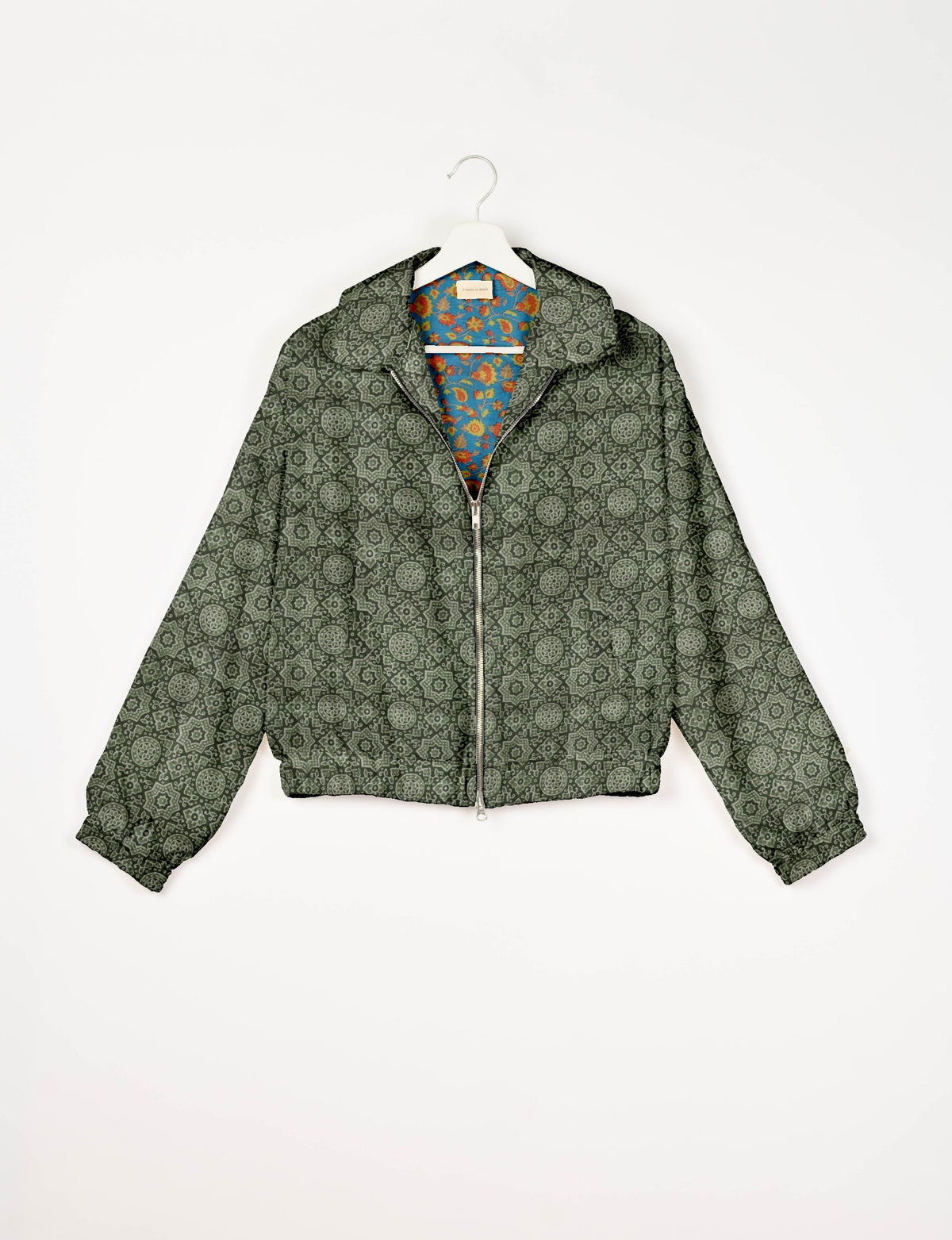Green bomber jacket with Indian ethnic pattern, front zipper, elastic cuffs, and floral inner lining, shown on hanger