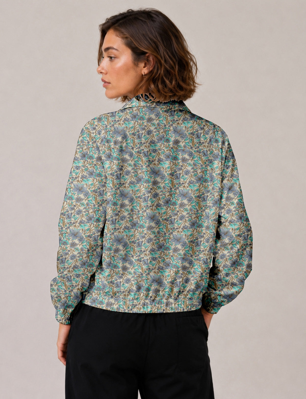 Woman wearing a yellow floral bomber jacket with front zipper, elastic cuffs, and side pockets, shown from front view