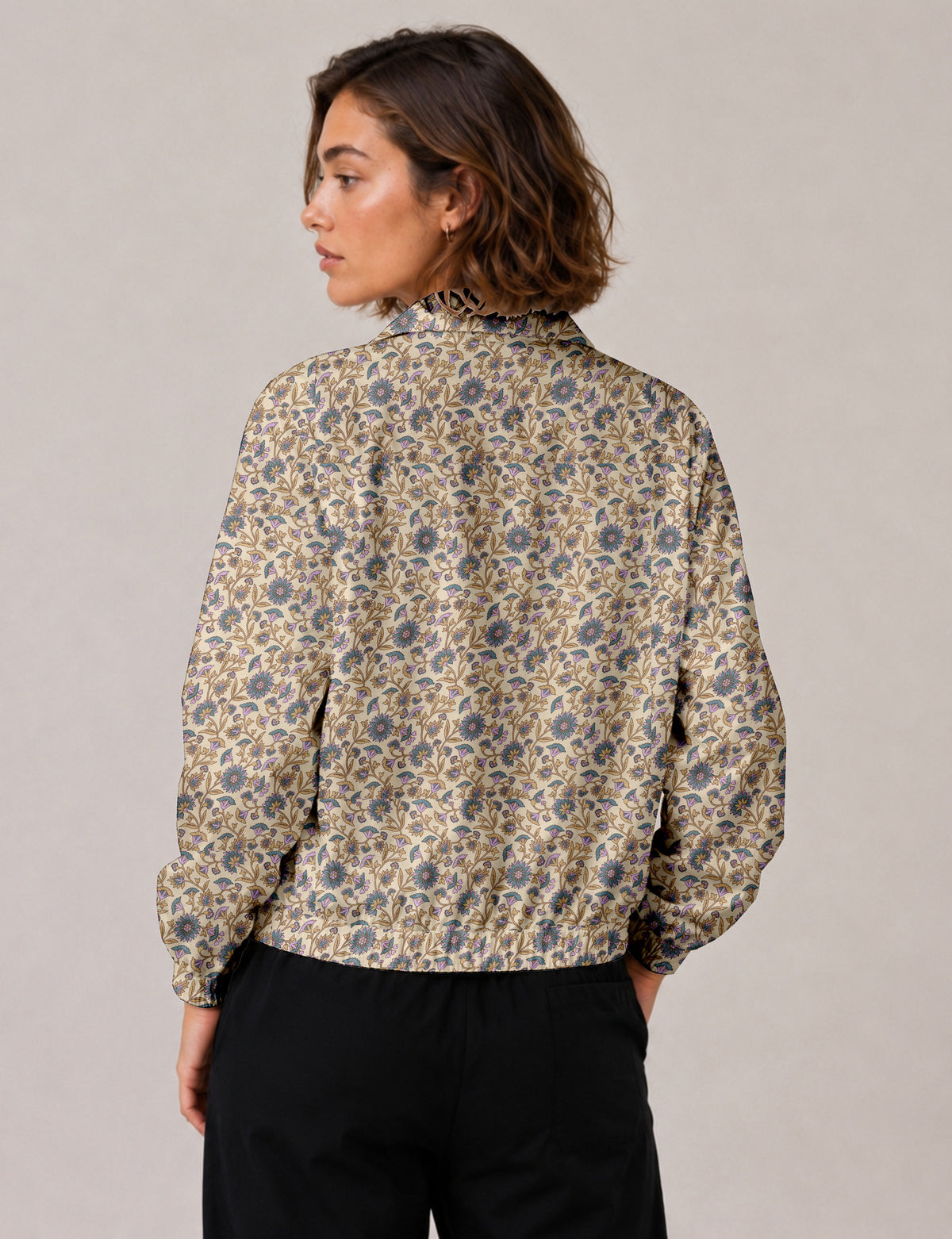 Woman wearing a yellow floral bomber jacket with front zipper, elastic cuffs, and side pockets, shown from front view