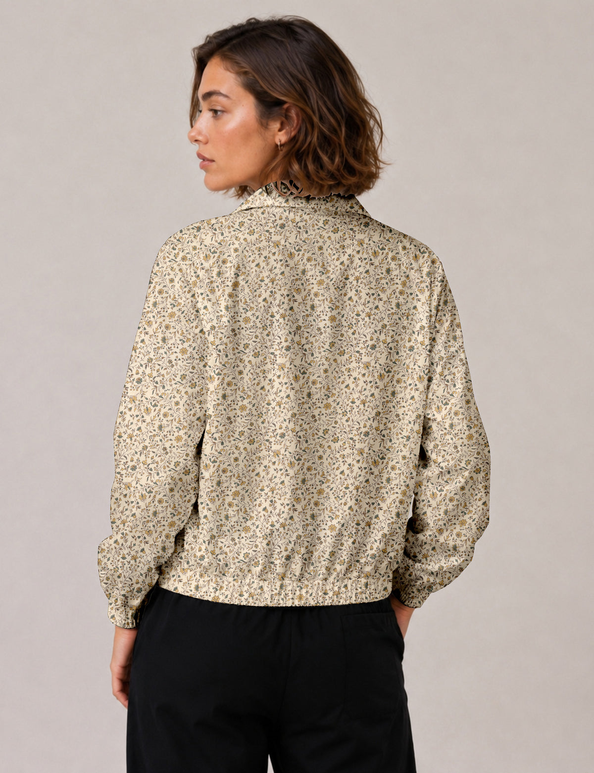Woman wearing a yellow floral bomber jacket with front zipper, elastic cuffs, and side pockets, shown from front view