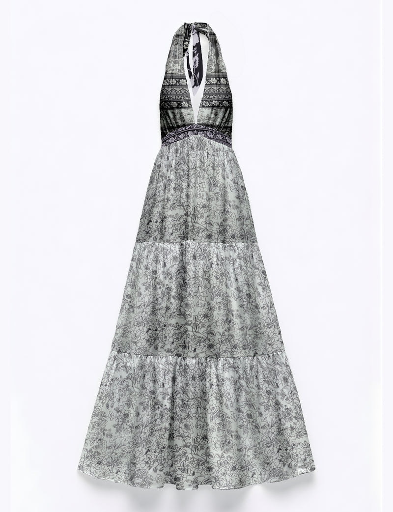 White maxi tiered dress with black floral and geometric tropical print, halter neckline, and deep V front, flat lay view