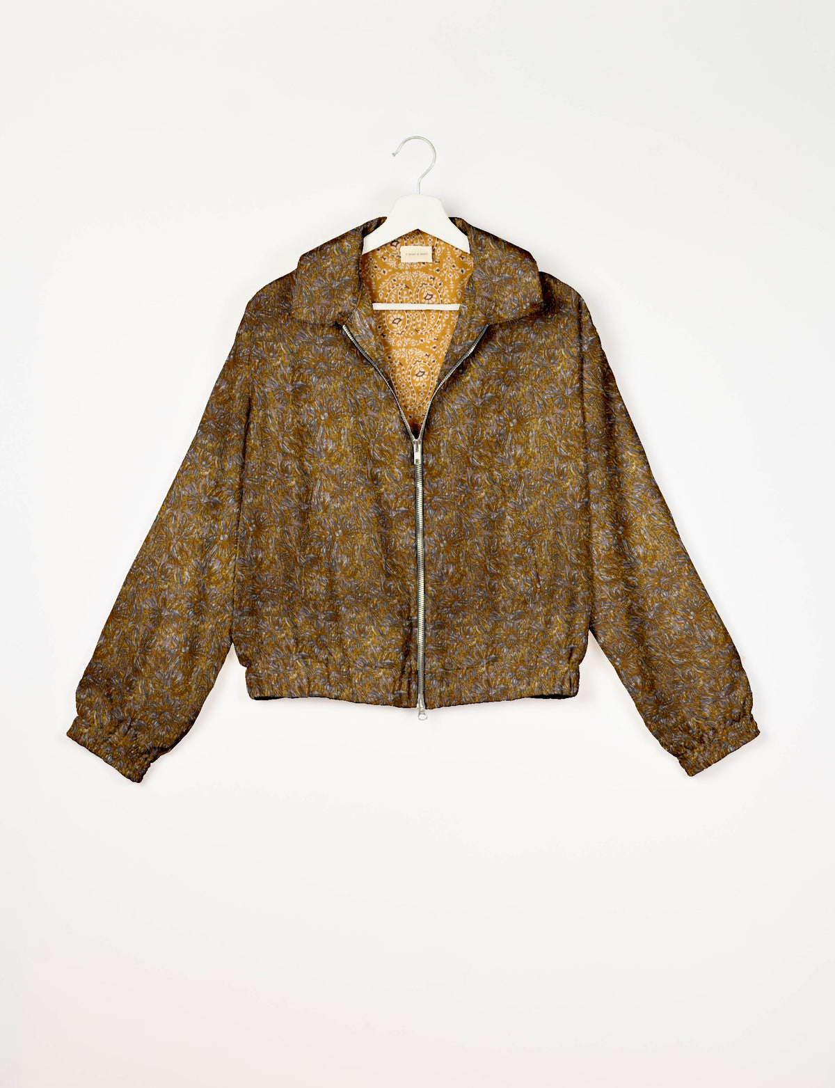 Yellow and brown abstract patterned bomber jacket with front zipper and elastic cuffs, shown on white hanger front view