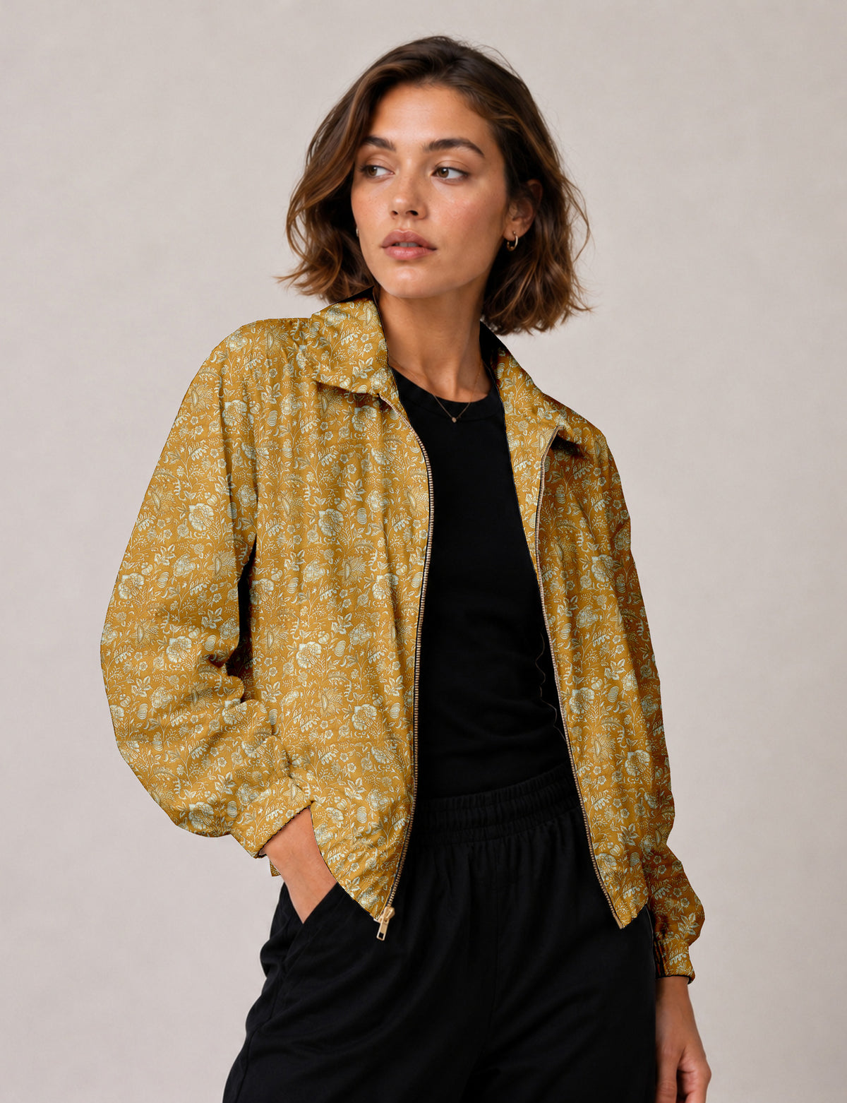 Woman wearing a yellow floral bomber jacket with front zipper, elastic cuffs, and side pockets, shown from front view