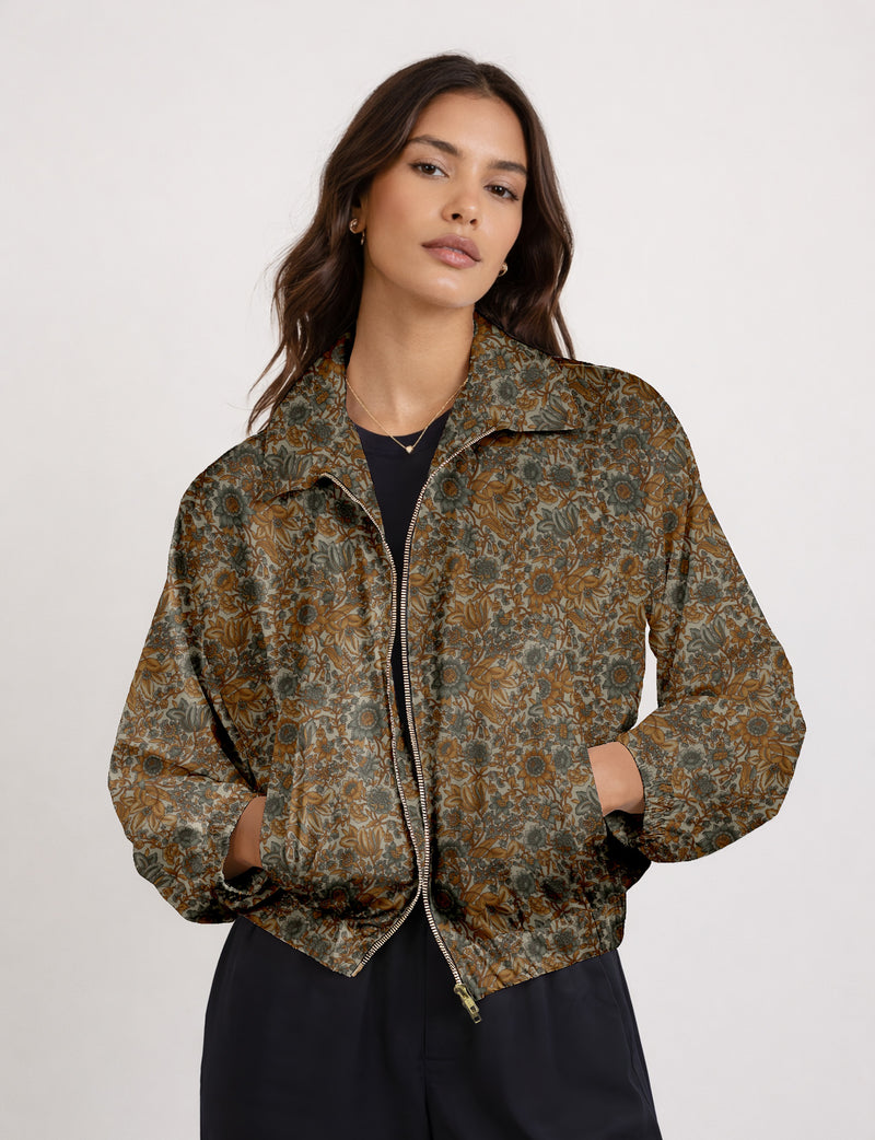 Woman wearing a yellow floral bomber jacket with front zipper, elastic cuffs, and side pockets, shown from front view