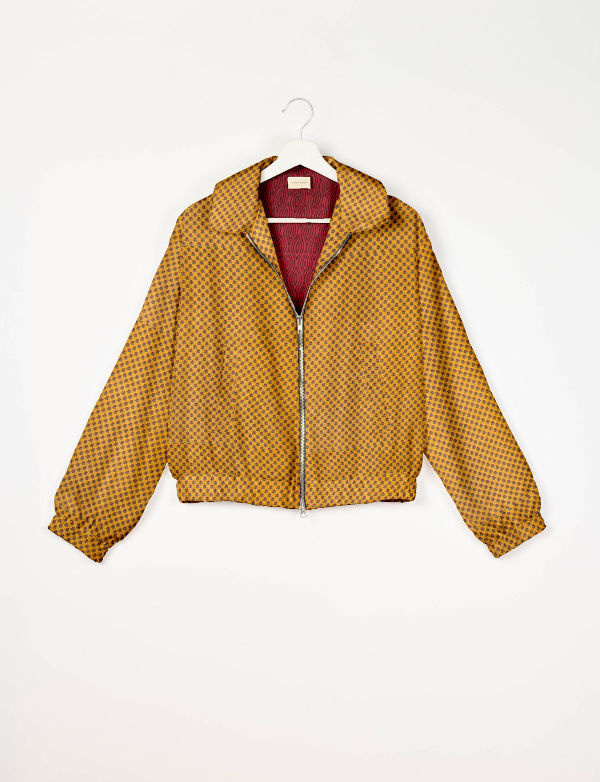 Yellow bomber jacket with small dark micro pattern, front zipper, elastic cuffs and waistband, shown on hanger front view