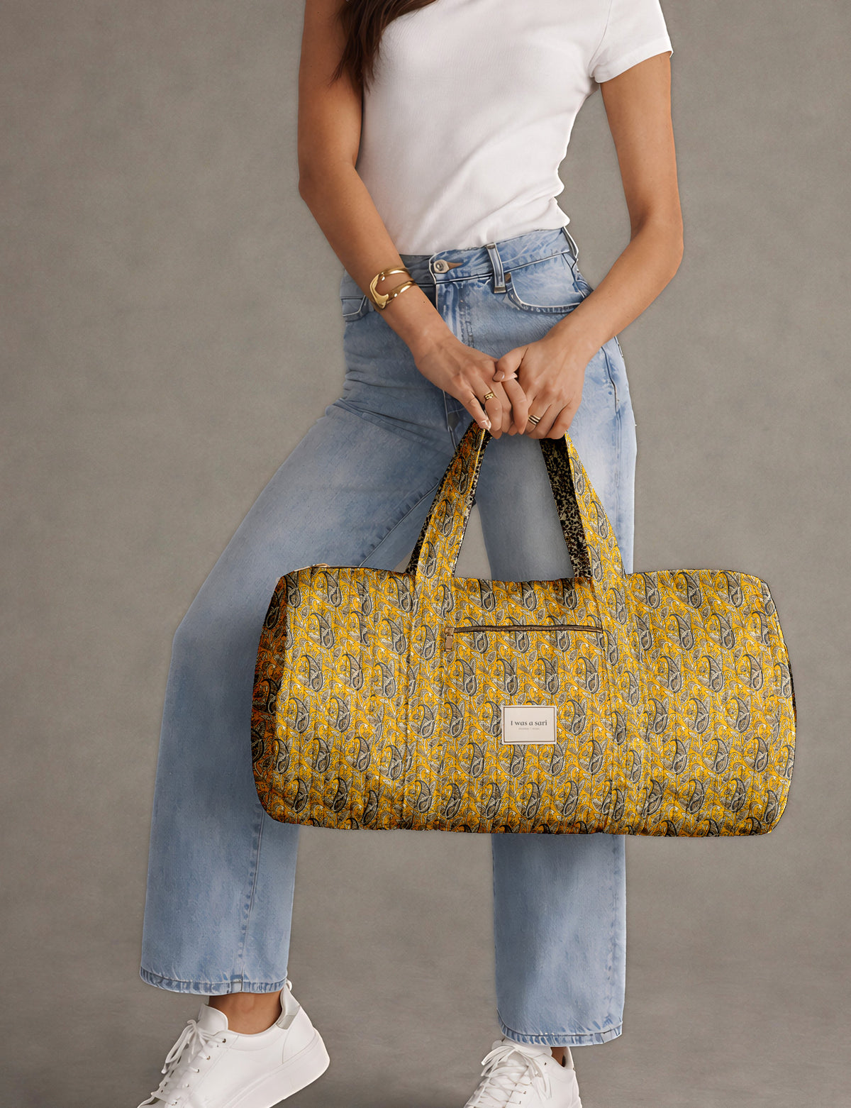 Brown paisley quilted bowling bag with dual handles, front zipper pocket, and "I was a sari" label on front side