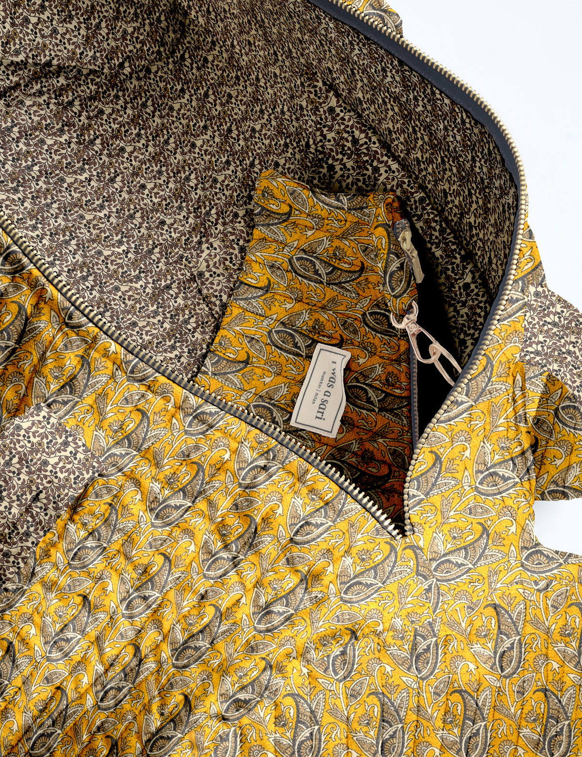 Brown paisley quilted bowling bag with front zipper pocket, held by person wearing white shirt and light blue jeans