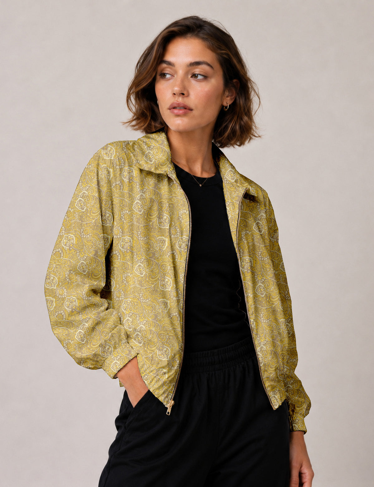 Woman wearing a yellow floral bomber jacket with front zipper, elastic cuffs, and side pockets, shown from front view