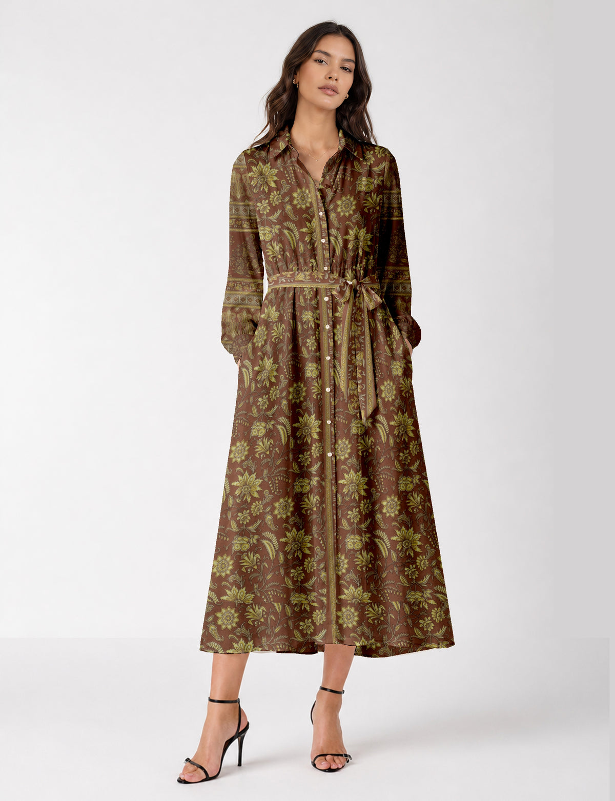 Woman wearing a brown long shirt dress with yellow floral tropical print, button front, tie waist, and long sleeves, front view