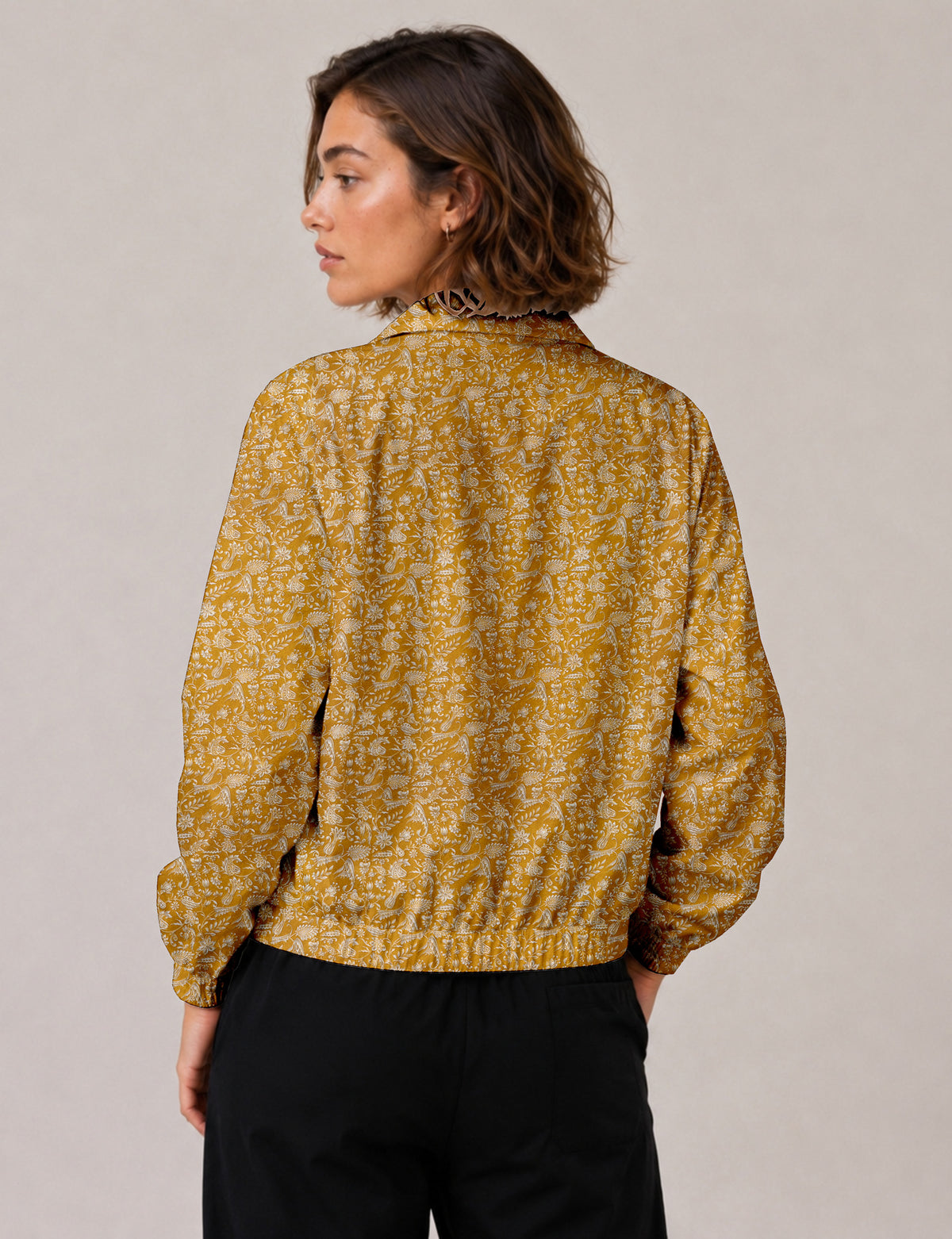 Brown floral bomber jacket with front zipper, elastic cuffs and hem, hanging on white hanger, red floral inner lining visible