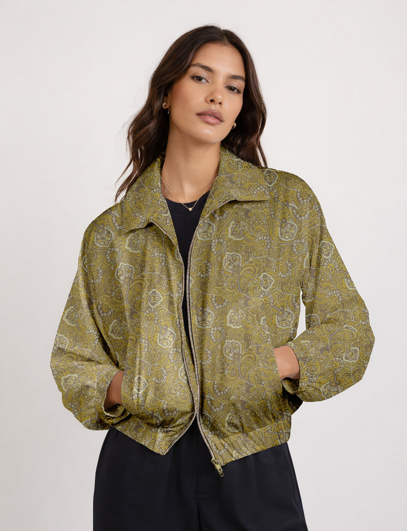 Woman wearing a yellow floral bomber jacket with front zipper, elastic cuffs, and side pockets, shown from front view