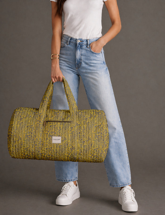 Woman carrying a quilted barrel bag in a yellow tropical sari print