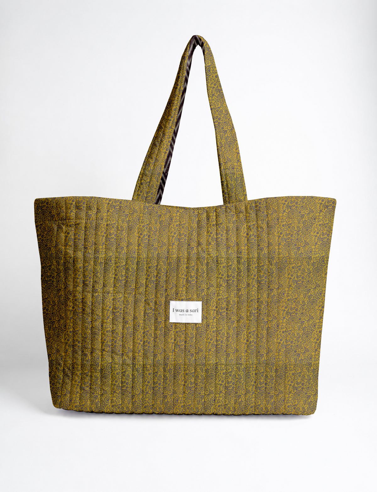 Quilted yellow tropical patterned beach bag with long handles and a white label reading "I was a sari" front view