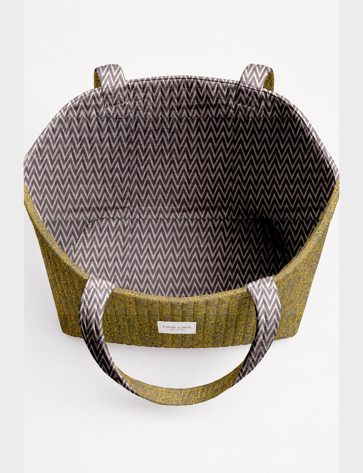 Quilted beach bag with yellow floral exterior and gray chevron patterned interior, shown open from top view