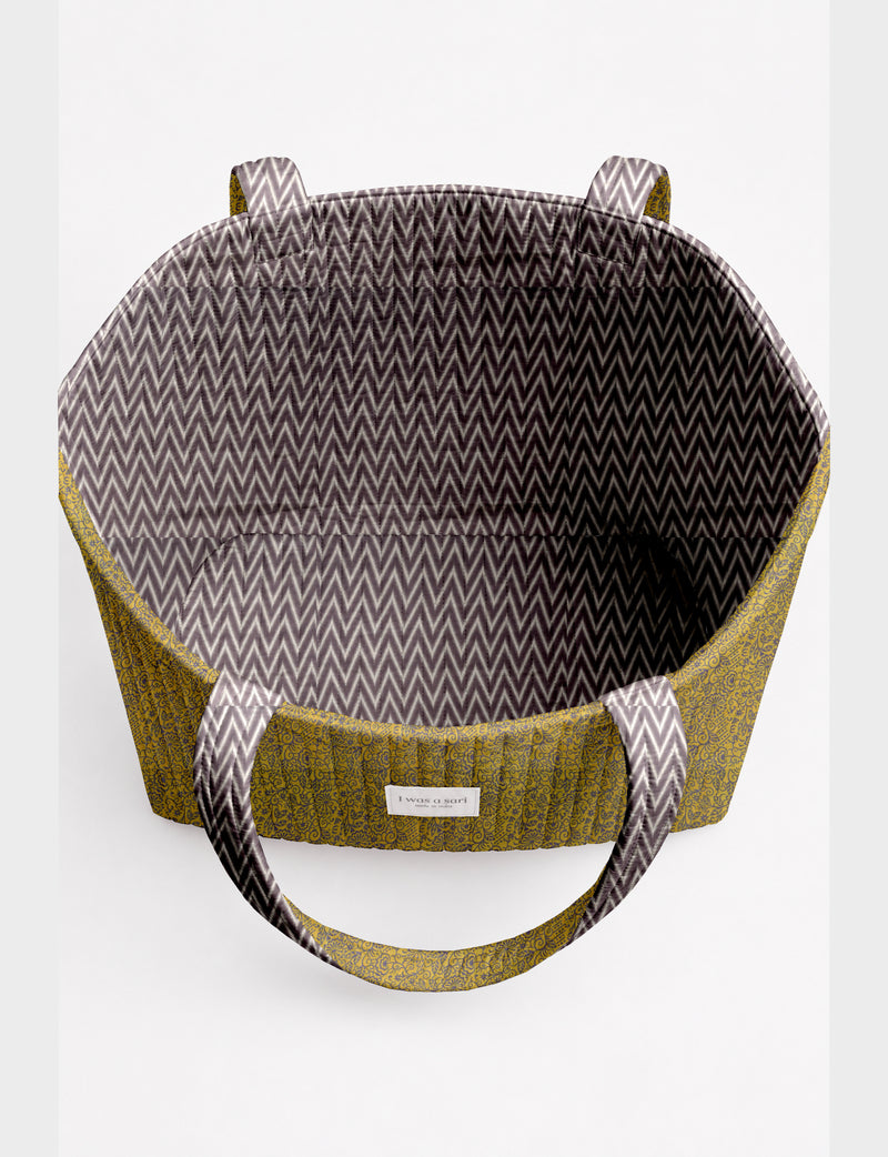 Quilted beach bag with yellow floral exterior and gray chevron patterned interior, shown open from top view