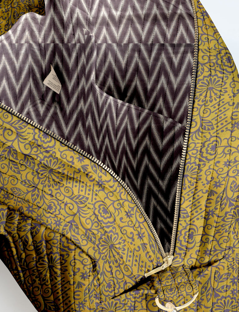 Quilted duffle bag with yellow floral pattern exterior and black and white chevron patterned interior, open zipper view