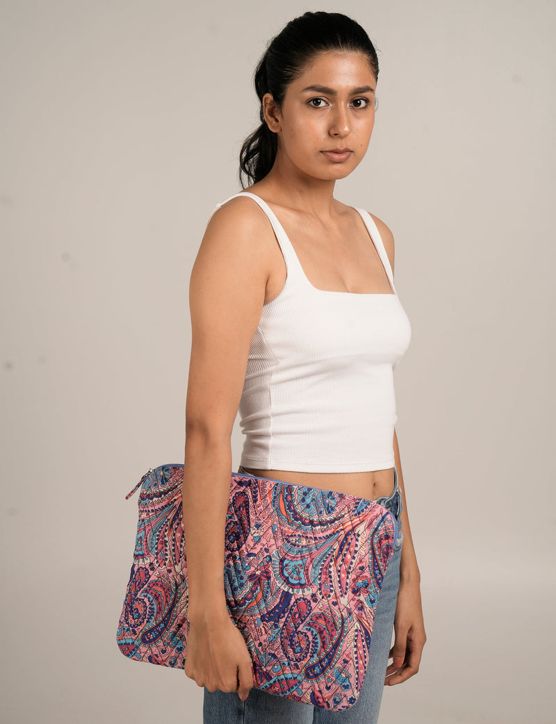 Woman wearing white ribbed tank top holding a pink and blue paisley patterned quilted laptop sleeve 15_16 in hand