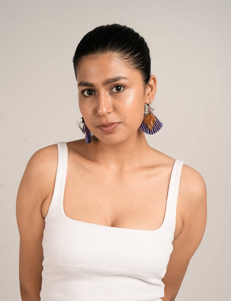 Model wearing pleated earrings with pink, purple, and gold abstract design, paired with a white ribbed tank top