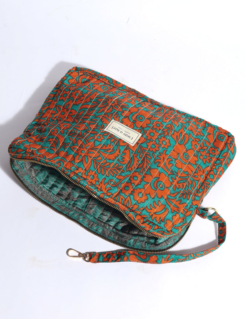Quilted fabric organizer with orange floral pattern on teal background, zipper closure, and detachable wrist strap, flat lay