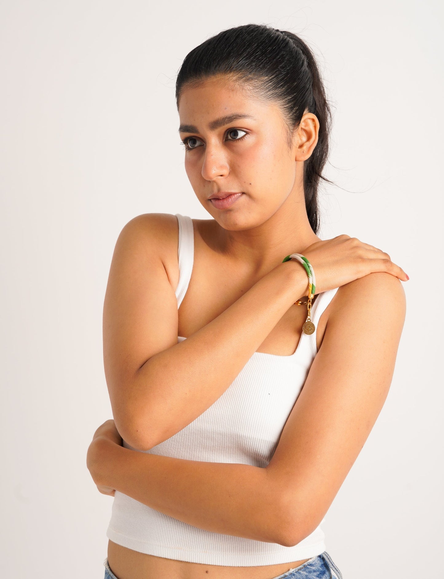 A close-up image of a hand wearing the Sari Rope Bracelete with Charm, showcasing its colorful threads and unique design. This accessory embodies ethical fashion and sustainability, crafted from repurposed saris for a stylish and eco-conscious statement.