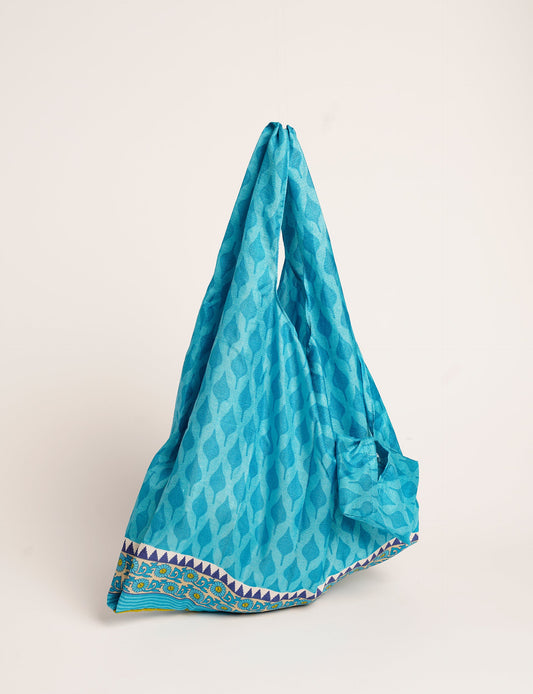 Stay eco-conscious with our Reusable Bag, handmade by Indian artisans from pre-loved saris. Silky and lightweight, this foldaway bag is perfect for your on-the-go lifestyle. Each piece is a unique statement of ethical fashion, embracing sustainability and style.