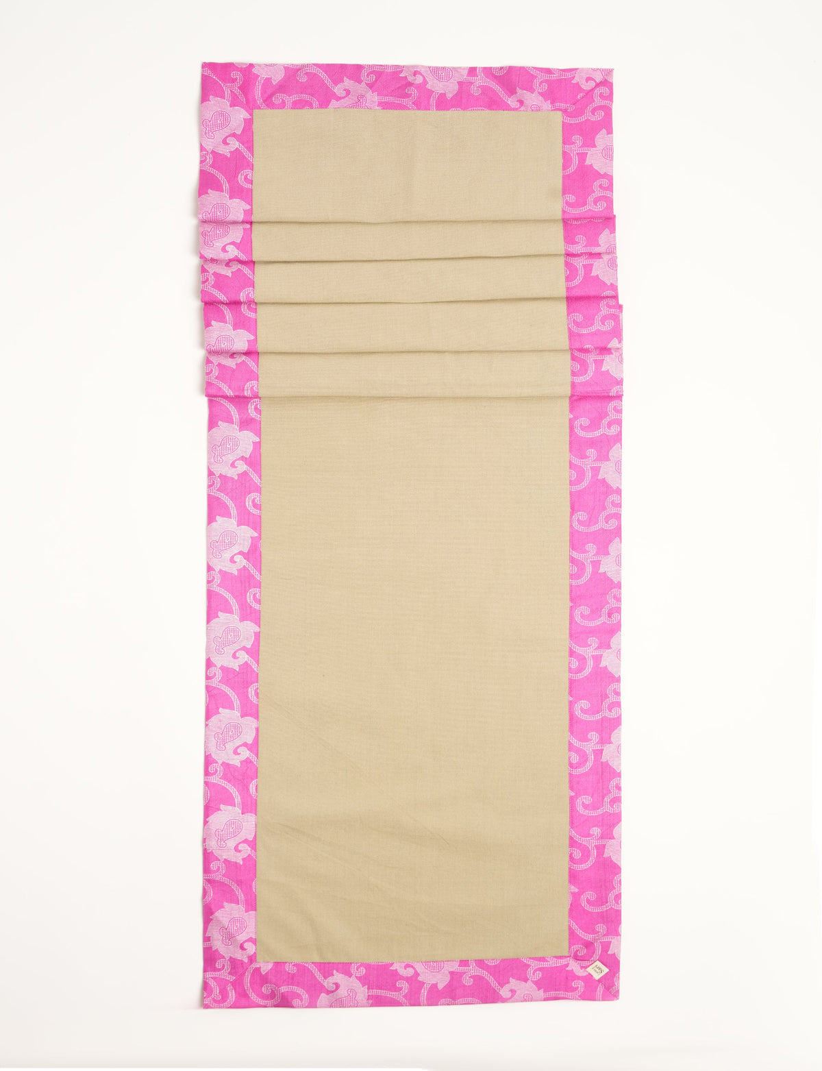 Rectangular beige table runner with bright pink ethnic floral border, shown flat with visible fabric texture and tag