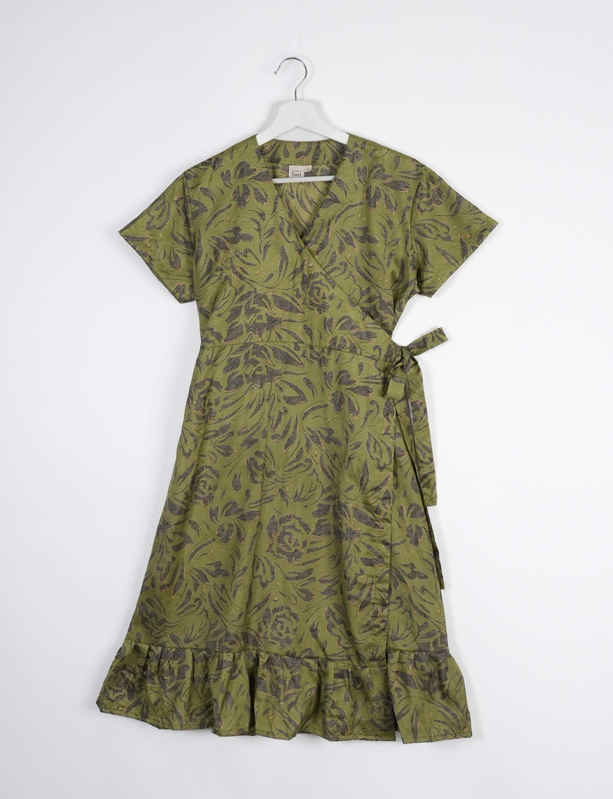 Embrace timeless elegance with our MIDI WRAP DRESS – a midi-length beauty featuring a v-neck, flattery from all angles, and a charming sari belt. Crafted from sustainable materials, this dress embodies ethical clothing and green fashion. Sophisticated with a frill tier at the hem and short cap sleeves, this dress is perfect for any occasion. Tie up the beautifully crafted sari belt on the side for a versatile, stylish, and eco-friendly look.