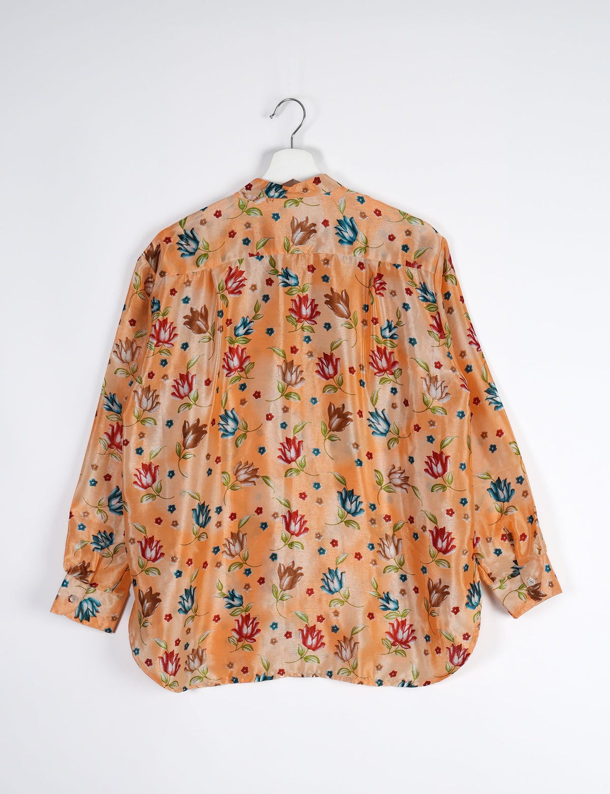 Orange longline shirt with red, blue, and brown floral print, buttoned cuffs, shown from back on white hanger