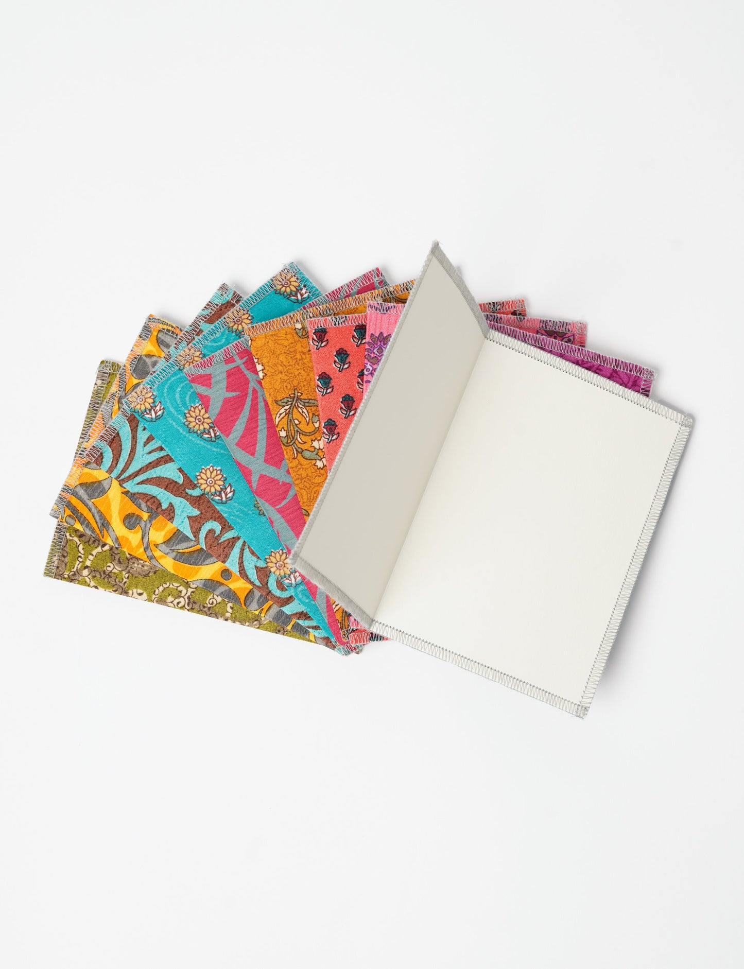 Sustainably crafted FOLDED POSTCARD SET, 10 assorted pieces made with 100% recycled paper and printed sari fabric sourced from Mumbai markets. Eco-friendly with contrast overlock edging. Envelopes included for eco-conscious gratitude and cheerful messages to loved ones.