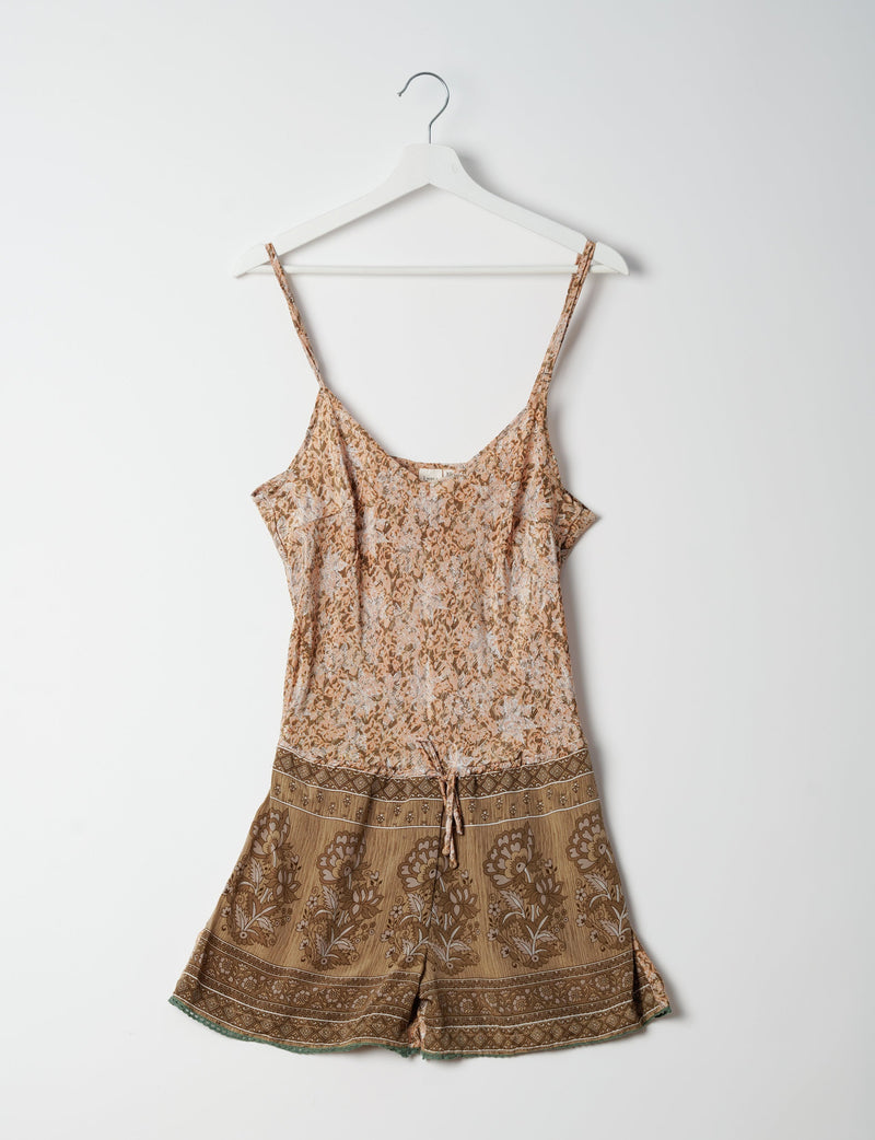 Beige playsuit with lace pattern, adjustable straps, drawstring waist, and floral print shorts hanging on white hanger